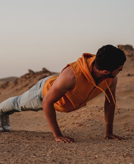 Man doet push-ups buiten in een droge, zandachtige omgeving