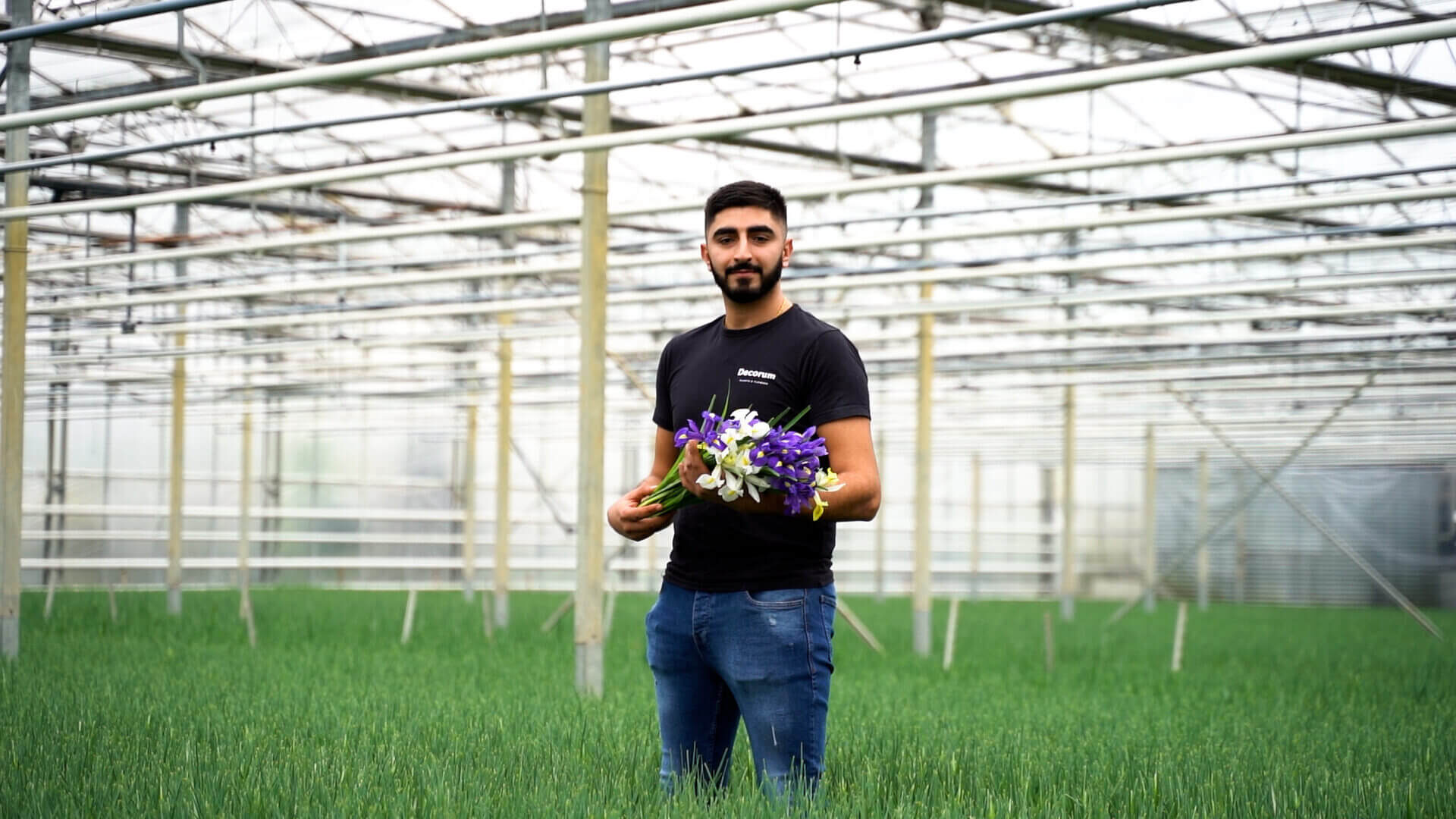 Medewerker in een kas houdt een bos bloemen vast tussen de planten